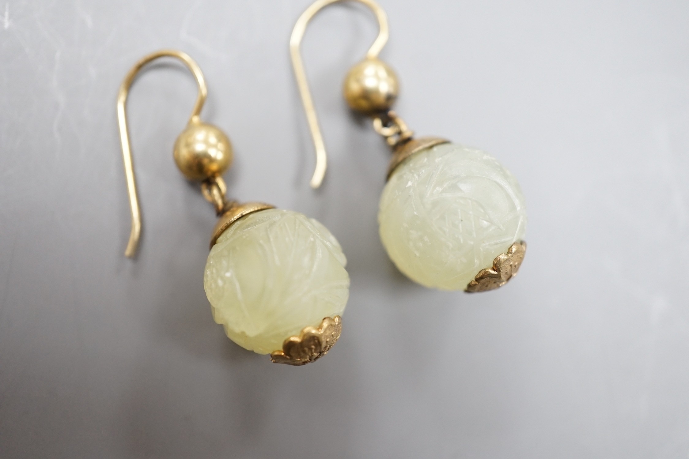 A pair of antique gilt metal and carved hardstone spherical drop earrings, jade diameter 14mm.